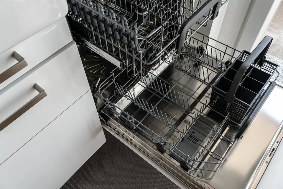 An open built-in dishwasher seen from above, with both racks pulled out