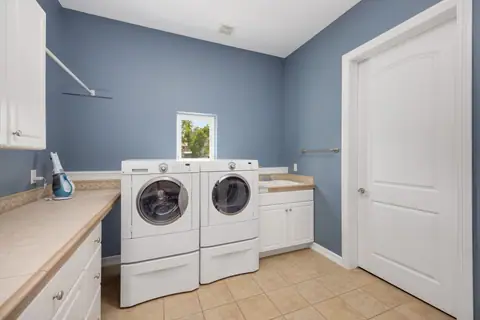 Clean and spacious laundry room featuring modern washing appliances and storage cabinets.