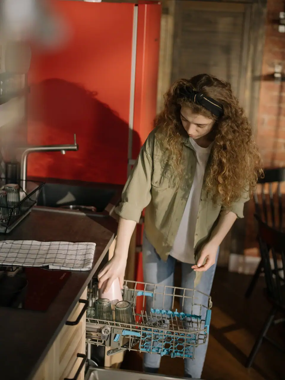 A woman loading glasses into the upper rack of a dishwasher